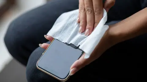 Kobieta czyści telefon nawilżoną chusteczką
